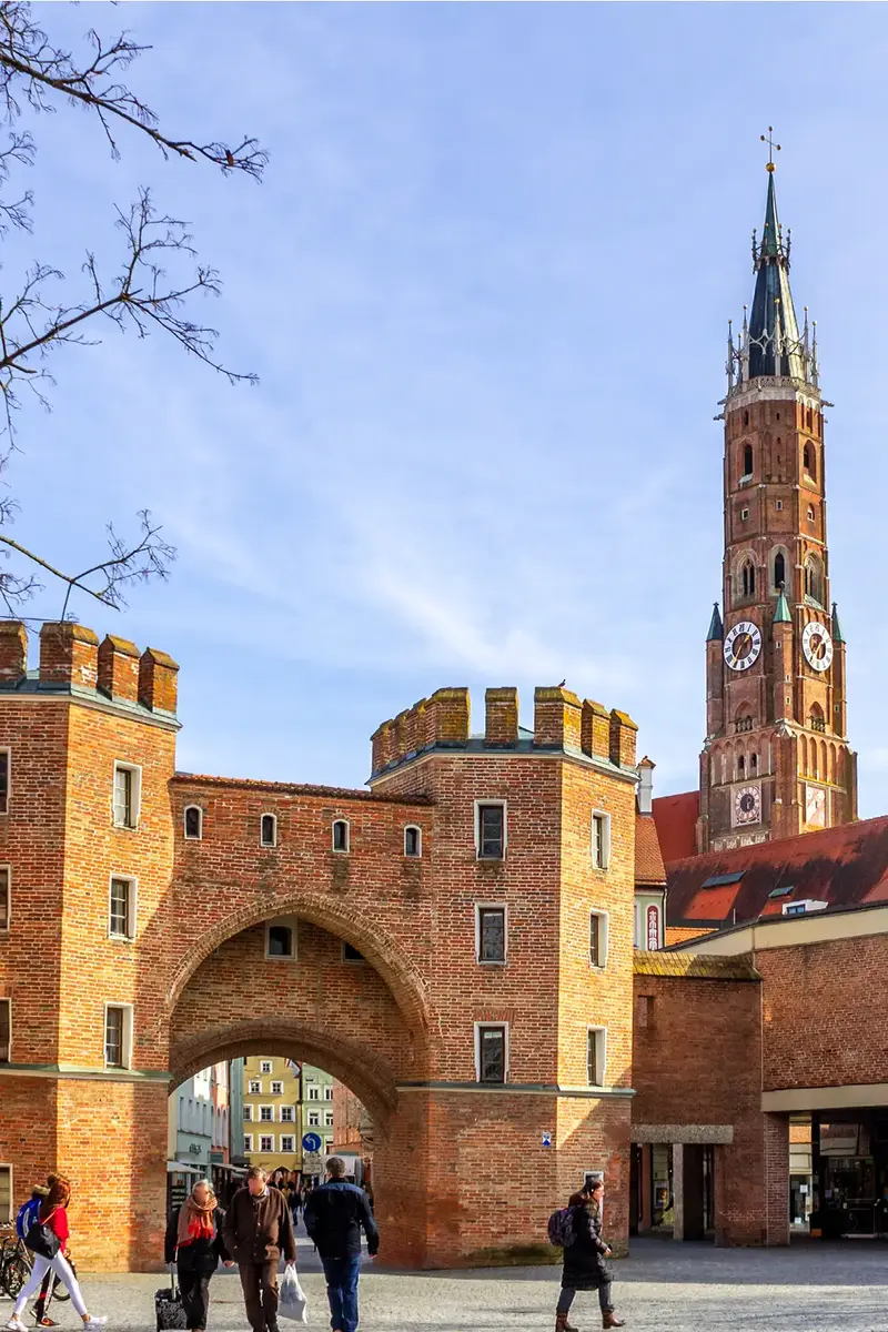 Eine belebte Szene in Landshut mit dem historischen Stadttor und dem Turm, wo die Kommunalwahl 2026 vorbereitet wird.