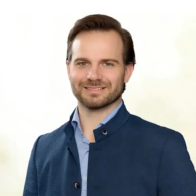 Ein lächelnder Mann in blauem Sakko präsentiert sich als Stadtratskandidat für die Kommunalwahl 2026 in Landshut.